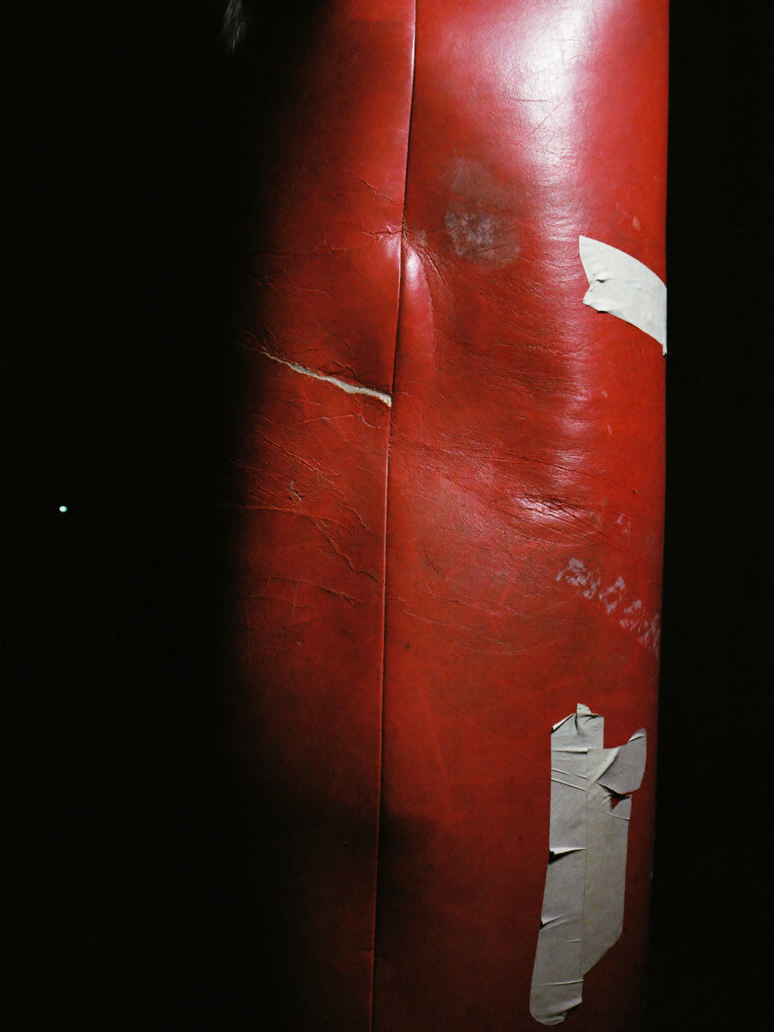 Macro of a scarred, taped-up leather heavy bag
