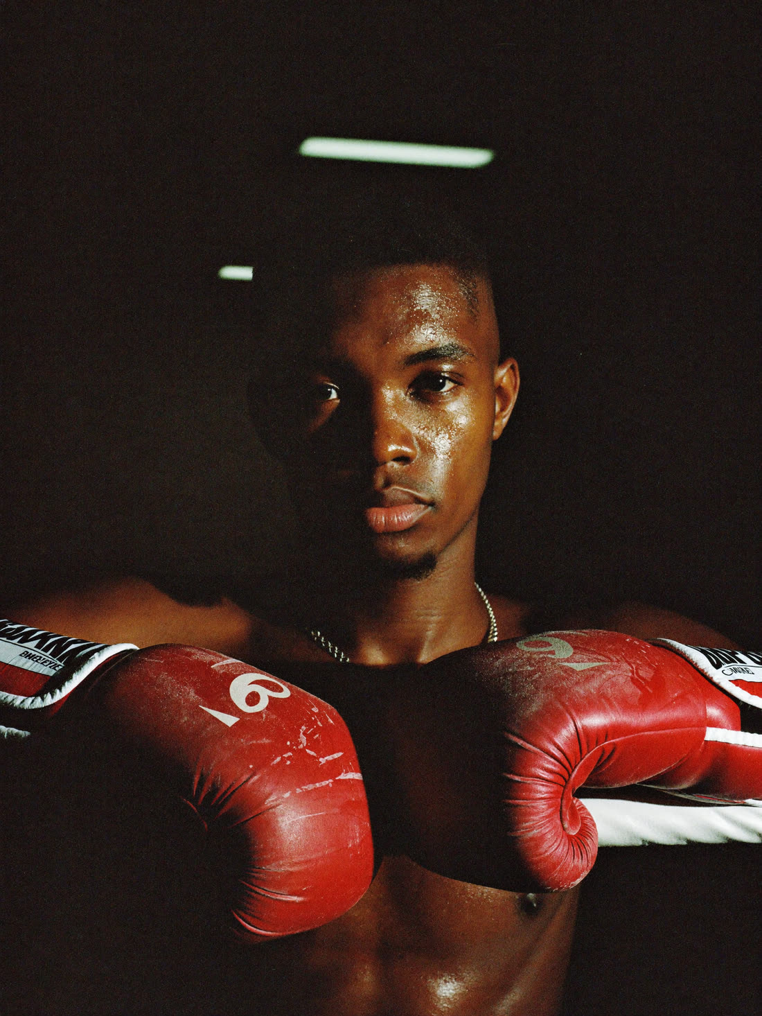 Portrait of coach Dre Okafor leaning on the ring ropes in red gloves